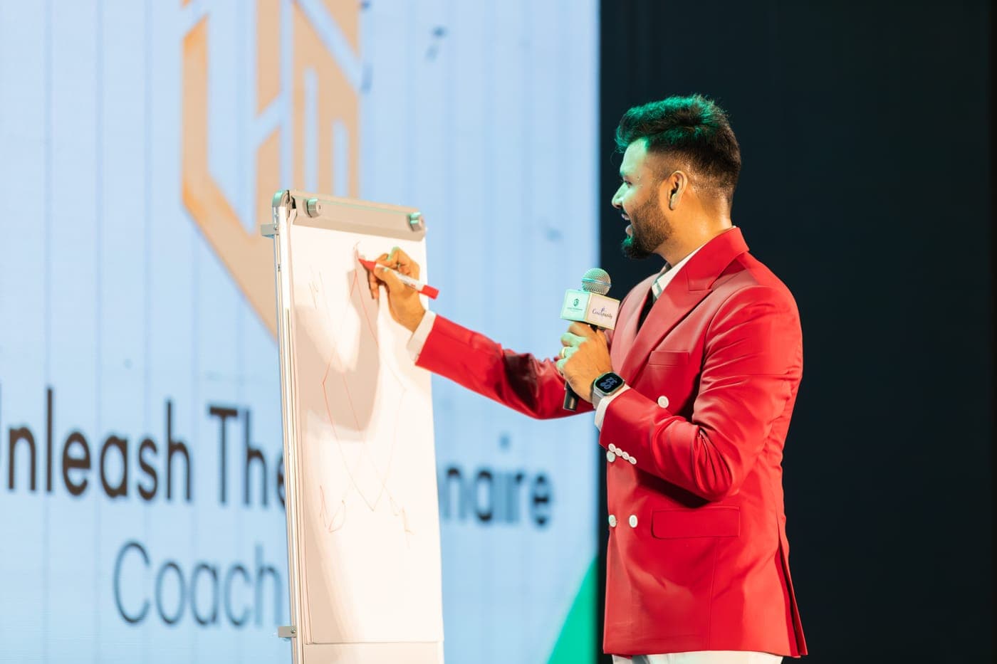 Purushottam teaching at a flipchart in front of the event backdrop